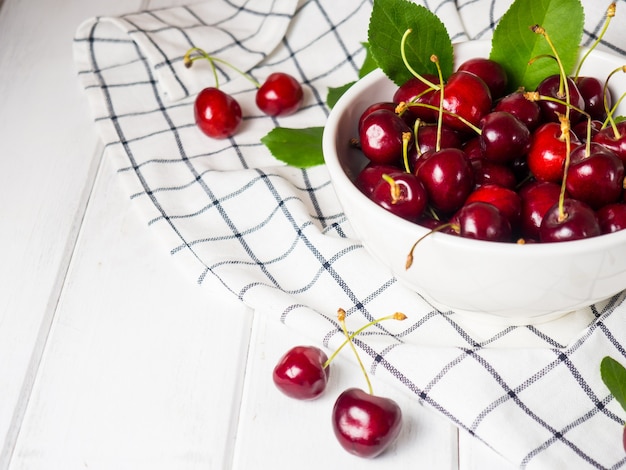 Fresh cherries in a white bowl on a white wooden table