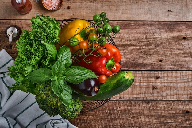 Fresh cherry tomato branches, basil leaves, napkin, pepper and pepper mill on old wooden rustic background. Food cooking background and mock up.