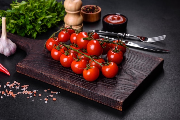 Fresh cherry tomatoes on a black background with spices