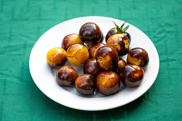 Fresh cherry tomatoes of different varieties on a plate on the blurred background closeup