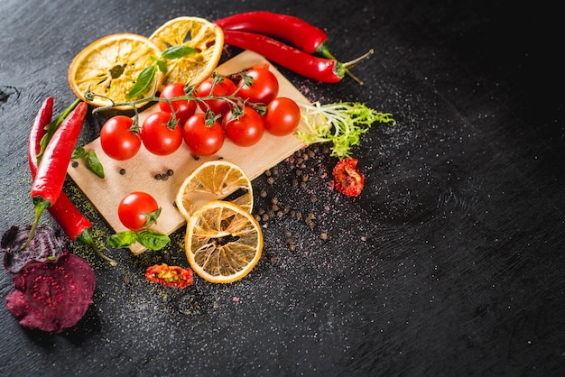 Fresh cherry tomatoes and spices on black background. Top view. Copy space