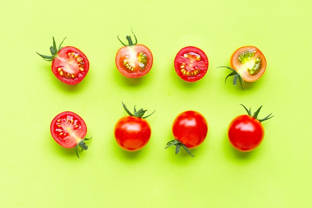 Fresh cherry tomatoes, whole and half cut isolated on green background.