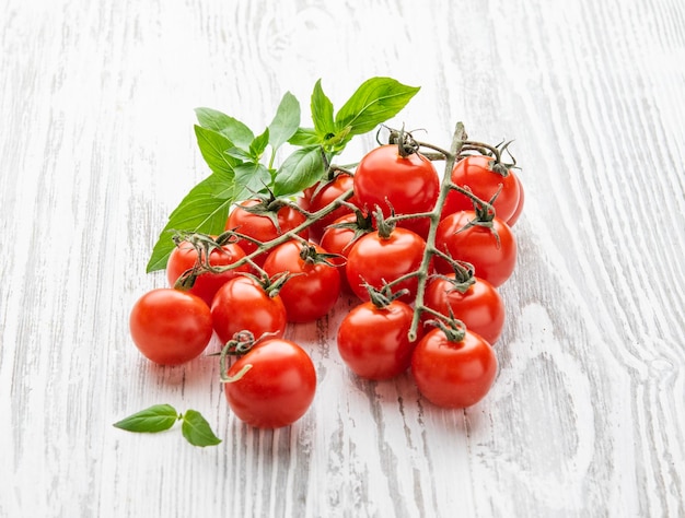 Fresh cherry tomatoes with basil on a white wooden background Farm healthy and ecofriendly vegetable