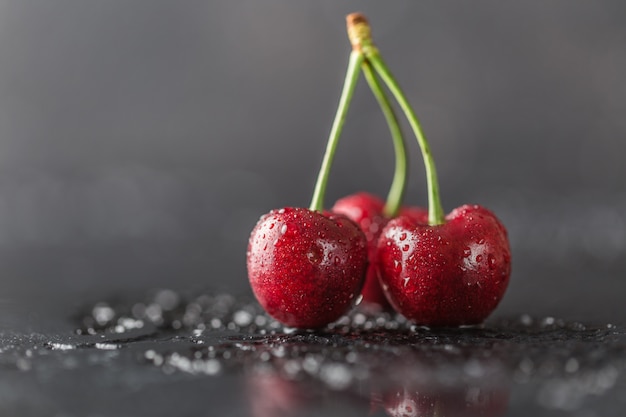 Fresh cherry with water drops on dark table.