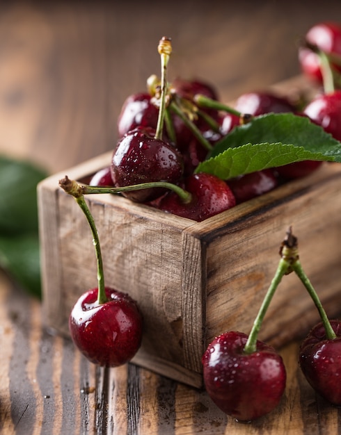 Fresh cherry with water drops on rustic wooden table.