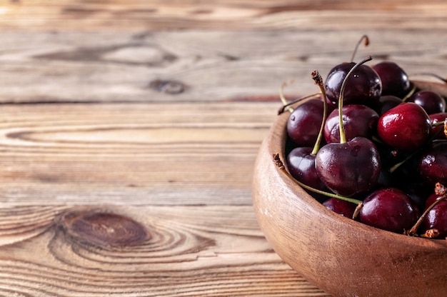 Fresh cherry in a wooden bowl on a rustic background. Copy space for text