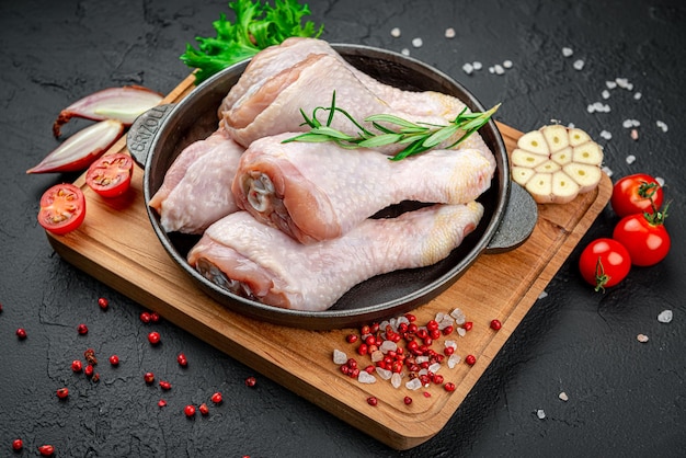 Fresh chicken drumsticks legs with ingredients for cooking in a frying pan