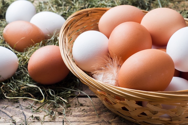 Fresh chicken eggs in a basket on straw on the farm