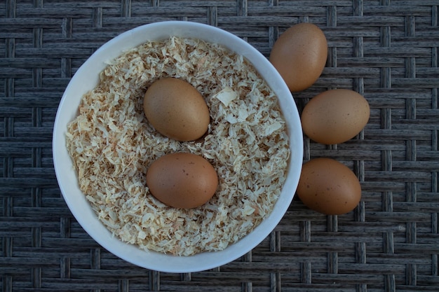 Fresh chicken eggs on sawdust in a plate on the table