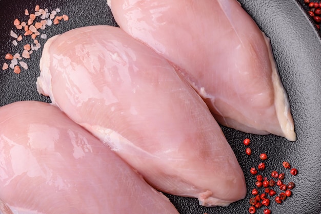 Fresh chicken fillet on a dark concrete table with spices and herbs