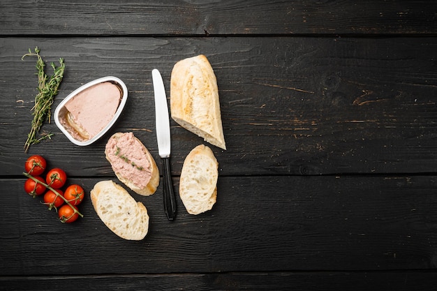 Fresh chicken liver pate from can on bread set, on black wooden table background, top view flat lay, with copy space for text