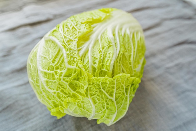 Fresh chinese cabbage, petsai or lettuce cabbage close-up on gray fabric texture