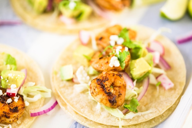 Fresh chipotle shrimp tacos with cotija cheese on a white corn tortillas.