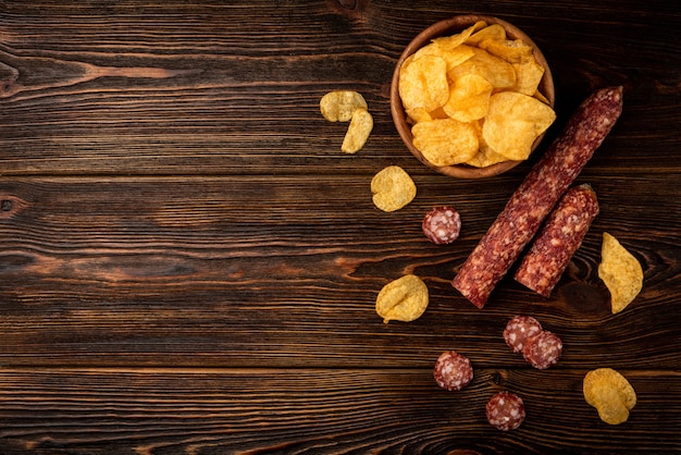 Fresh chips with sausage on a wooden table