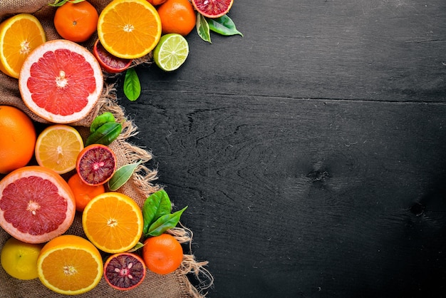 Fresh citrus fruits Lemon orange tangerine lime On a black background Wooden Top view