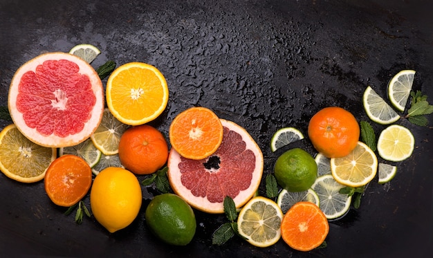 Fresh citrus fruits - Lemons, oranges, limes, grapefruits on black surface