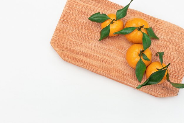 Fresh citrus fruits tangerine or mandarin on board on white background. Flat lay. Copy space. Frame from bright tasty tangerines.