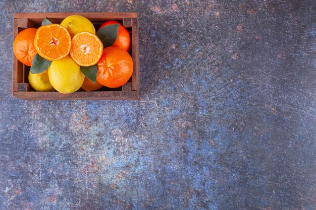 Fresh citrus fruits with leaves placed in a wooden old box . 