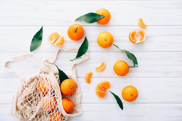 Fresh clementines with leaves on white wooden table.