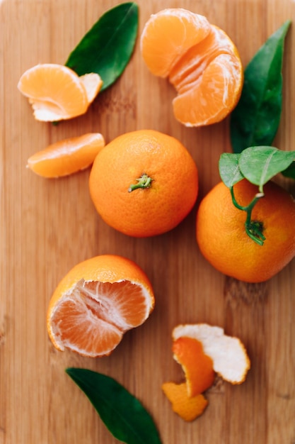 Fresh clementines with leaves on wooden table, top view