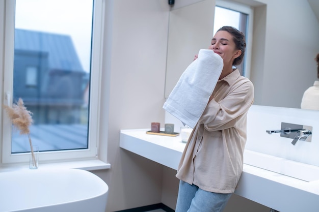 Fresh clothes. A woman smelling fresh towel after washing