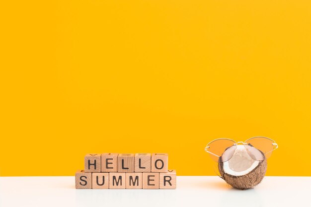 Fresh coconut wearing sunglasses on color background Hello summer