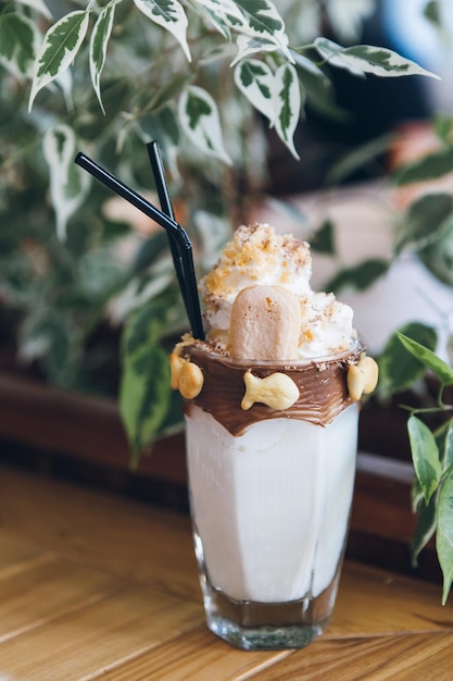 Fresh cold delicious milkshake in a tall glass with tubes, decorated with cream, chocolate paste and cookies. Toning.