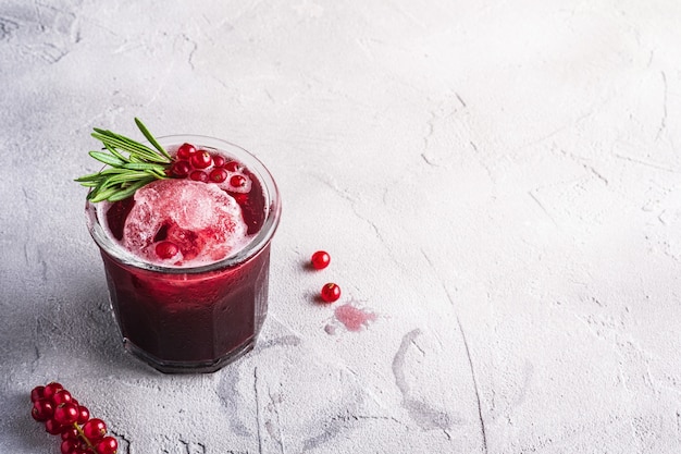 Fresh cold fruit cocktail in glass, refreshing summer red currant berry drink with rosemary leaves