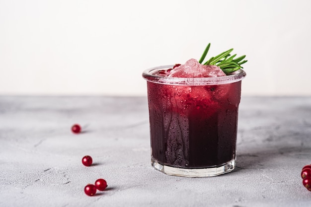 Fresh cold fruit cocktail in glass, refreshing summer red currant berry drink with rosemary leaves