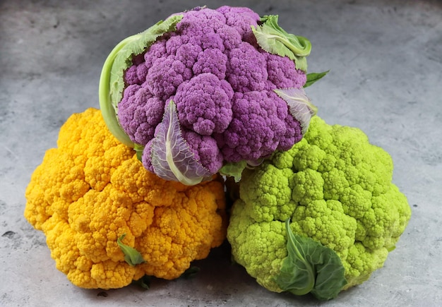 Fresh colorful cauliflowers on grey background, side view. Healthy eating. Vegan food. Multicolored