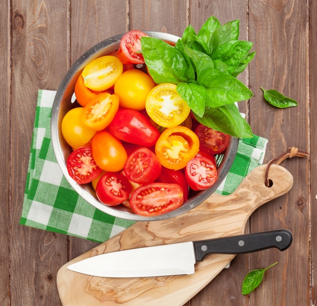 Fresh colorful tomatoes and basil in colander. Top view