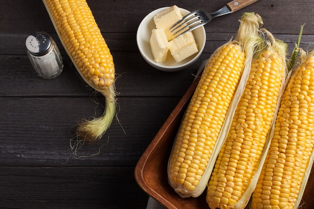 Fresh corn on cobs on rustic wooden table.