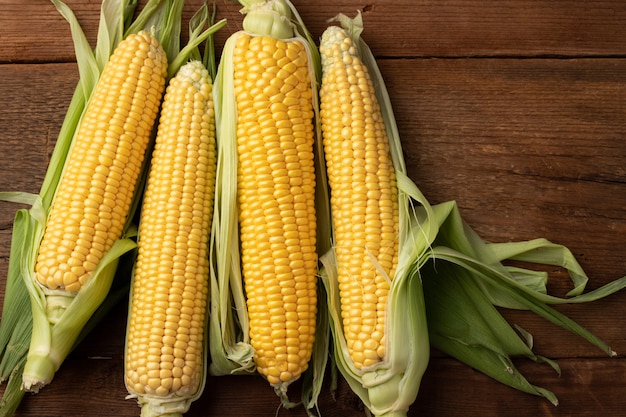 Fresh corn on cobs on rustic wooden table.