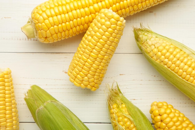 Fresh corn on cobs on white wooden background