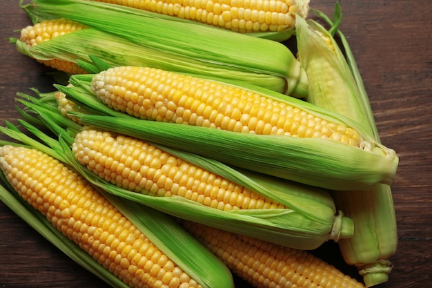 Fresh corn on cobs on wooden table closeup