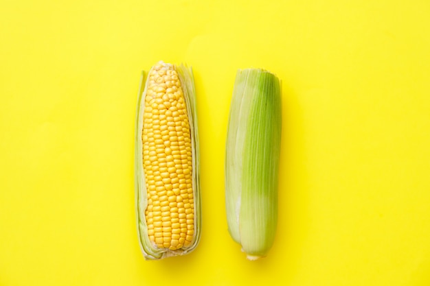 Fresh corn on cobs on yellow table, closeup, top view