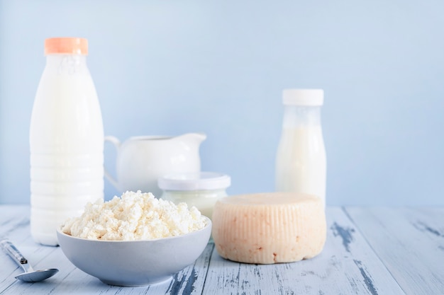 Fresh cottage cheese and bottles of mik on blue background