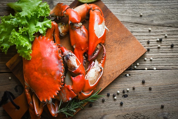 Fresh crab on wooden plate boiled or steamed crab red in the restaurant claw crab cooking food seafood plate with chili herbs spices salad