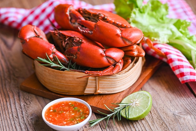 Fresh crab on wooden steamer and seafood sauce herbs spices lemon lime salad seafood crab cooking food steamed crab red in the seafood restaurant kitchen top view