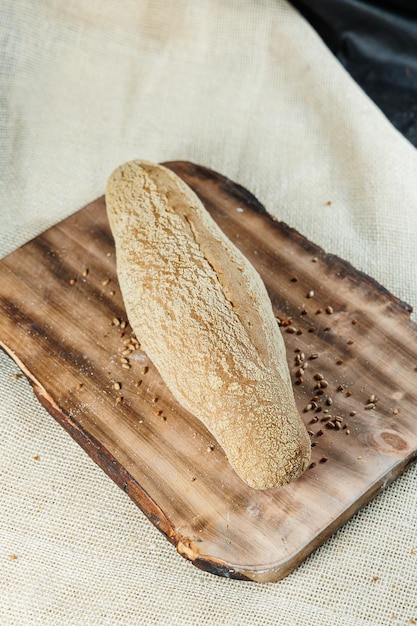 Photo fresh craft bread sliced on a wooden board on a dark concrete background homemade baking