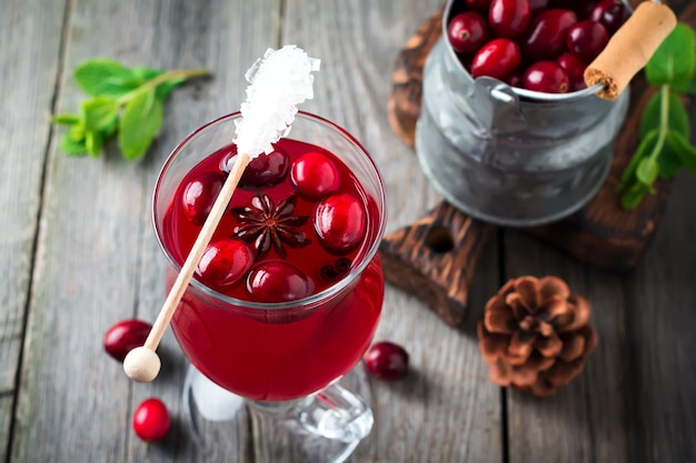 Fresh cranberry juice with cinnamon and anise in glass jars on the old wooden surface. Selective focus.Top view.