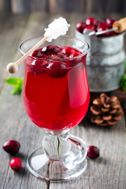 Fresh cranberry juice with cinnamon and anise in glass jars on the old wooden surface. Selective focus.