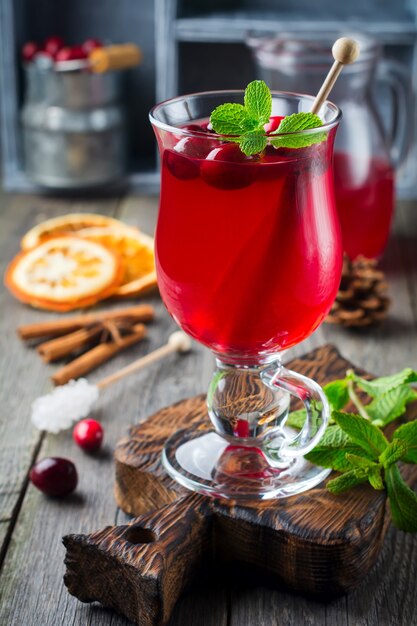 Fresh cranberry juice with cinnamon and anise in glass jars on the old wooden surface. Selective focus.