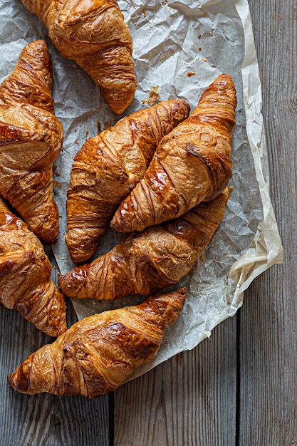 Fresh crispy french croissants on a wooden background. Traditional ruddy puff pastry (buns)