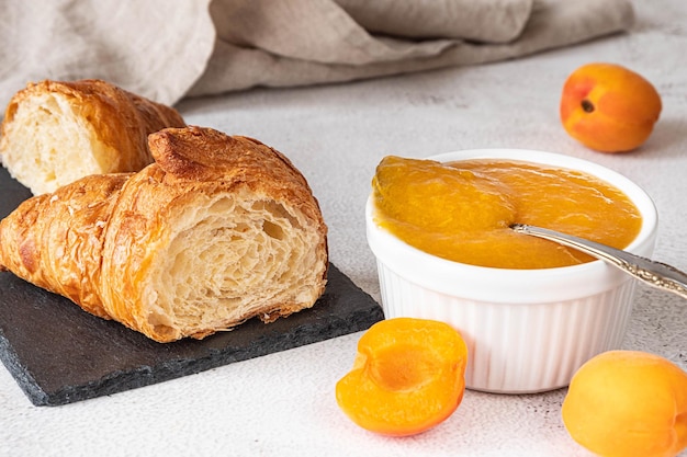 Fresh croissant cut in two halves and served with apricot jam. French breakfast concept