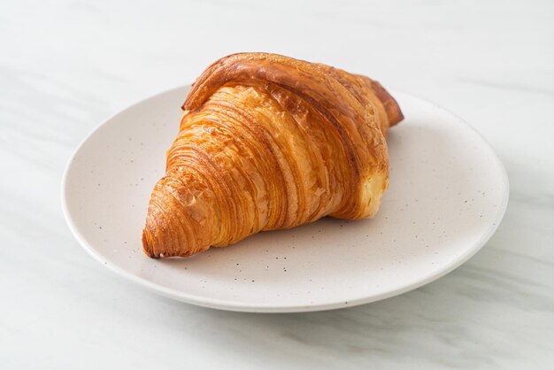 fresh croissant on white plate with black coffee