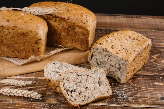 Fresh crunchy bread loafs and pieces on the wooden background