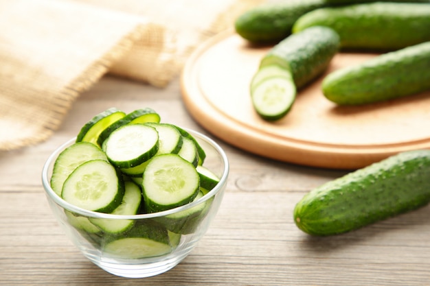 Fresh cucumber slices in bowl on grey wooden background