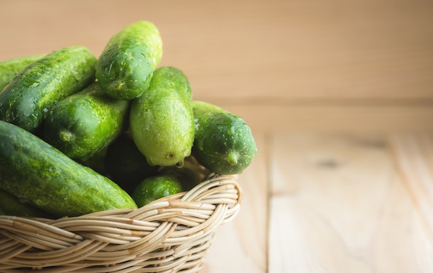 Fresh cucumbers in basket on wood