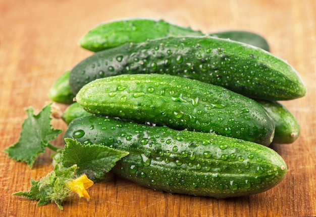 Fresh cucumbers with green leaves on wooden background